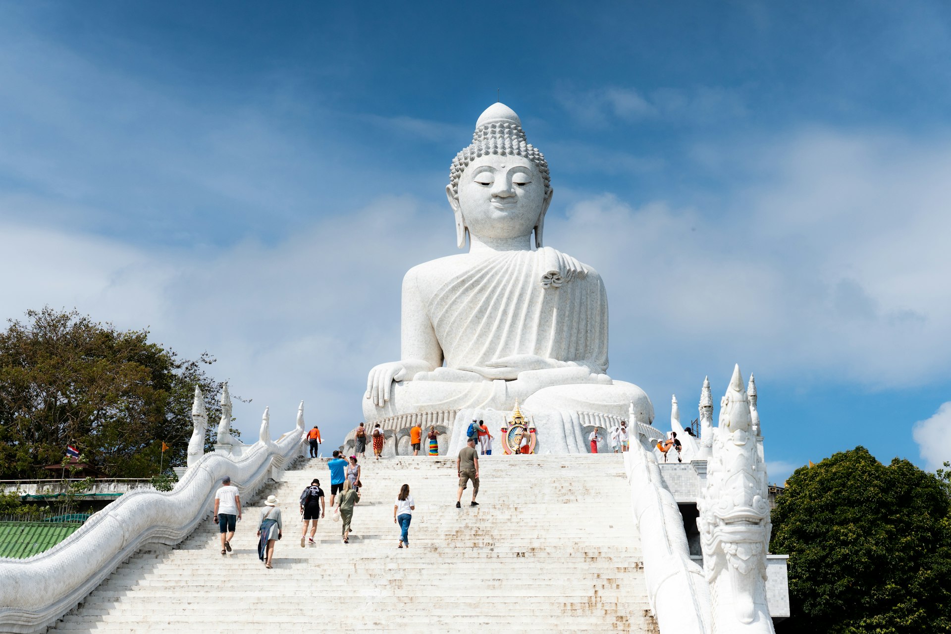 a large white buddha statue sitting on top of a set of stairs