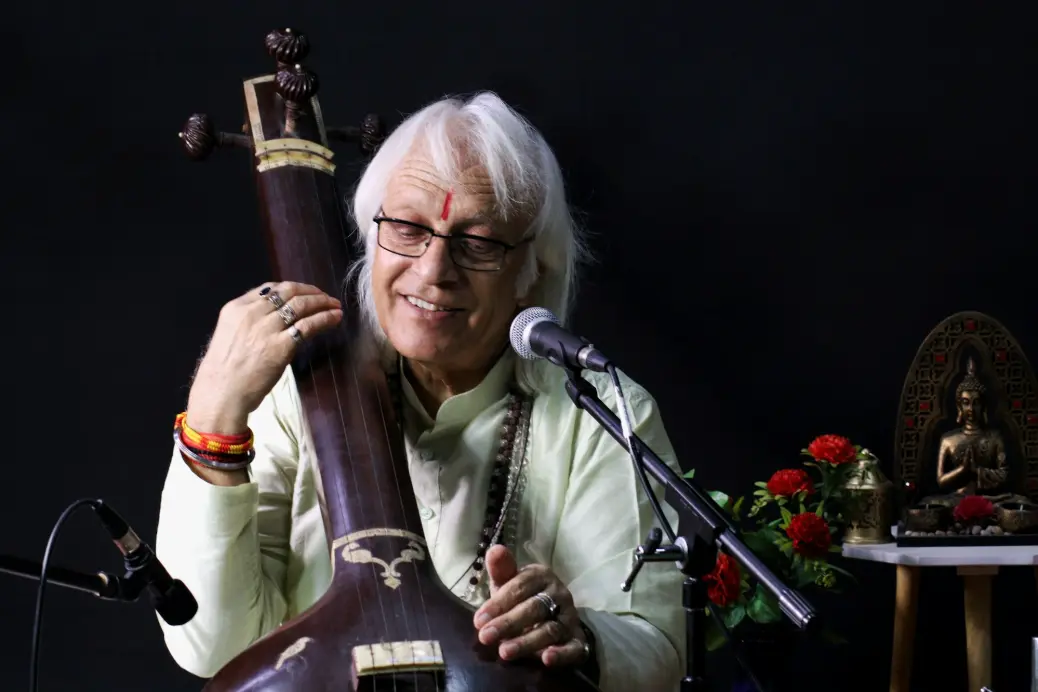 a man holding a musical instrument in front of a microphone