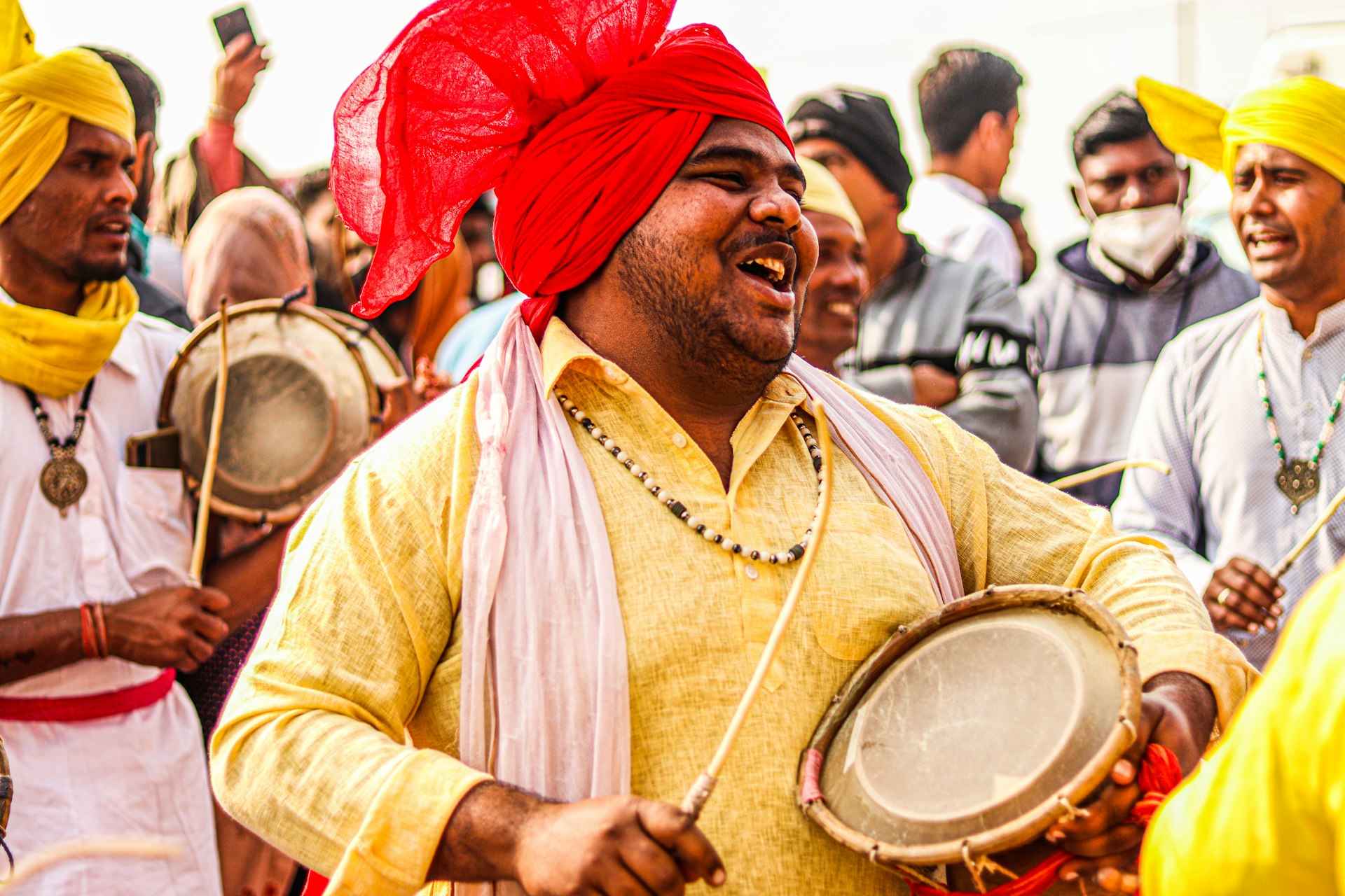 a man with a red turban is holding a drum