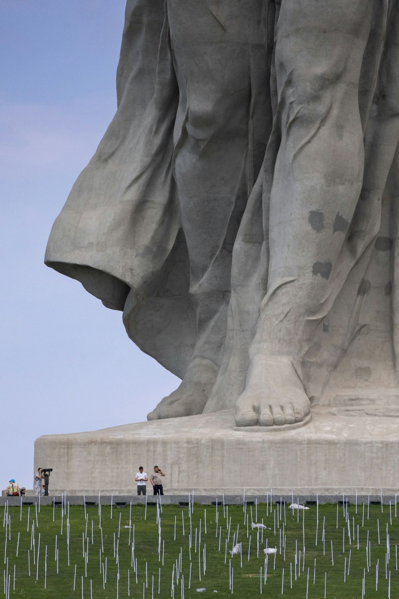 Two people stand at the base of a colossal stone statue.