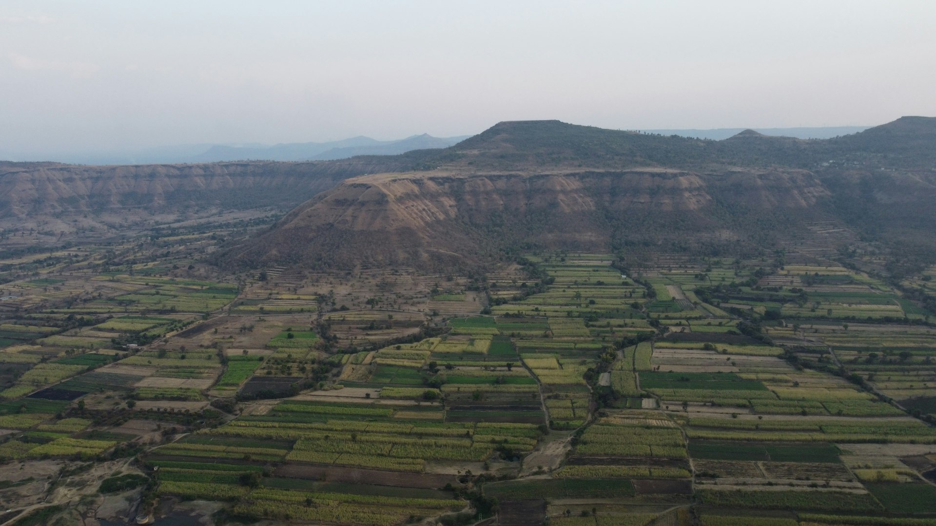 an aerial view of a valley with a mountain in the background