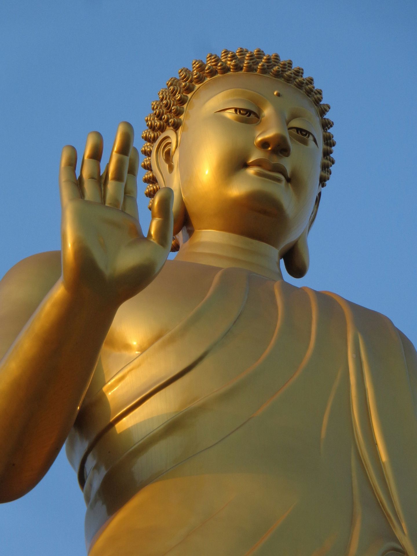 Golden buddha statue raising its hand.