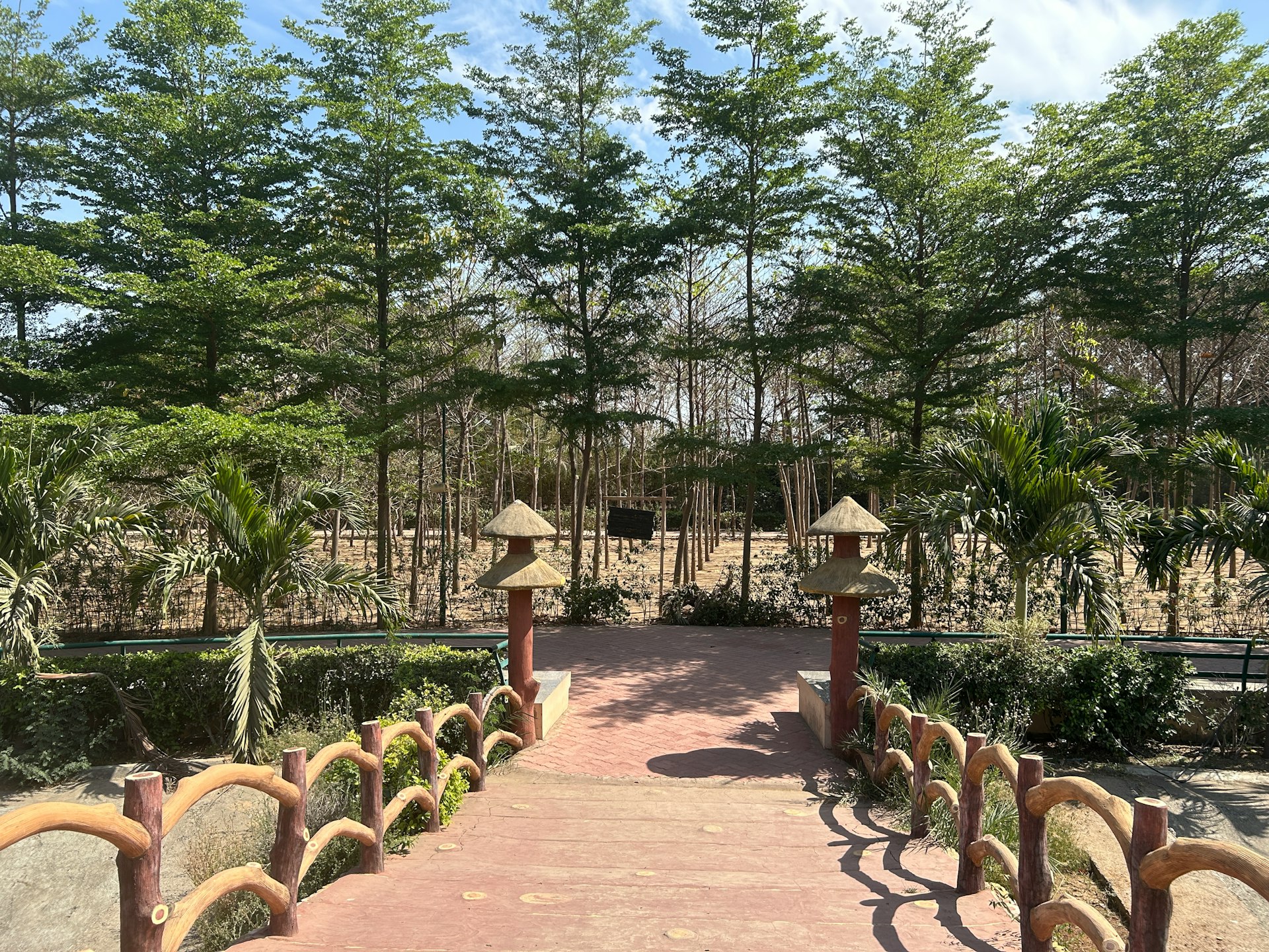 A red bridge leads to a lush garden path.