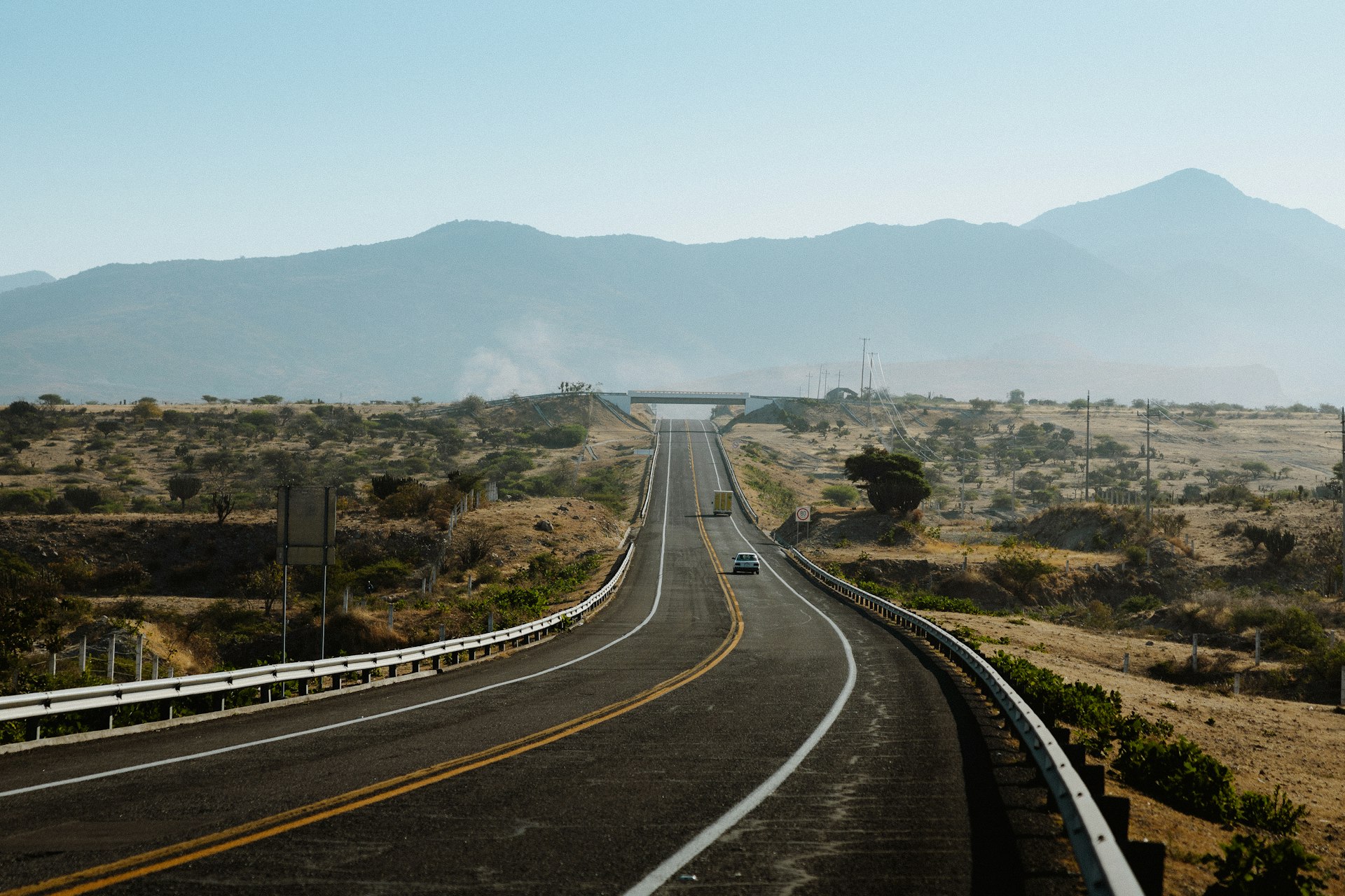 A road winds through a hazy, mountainous landscape.