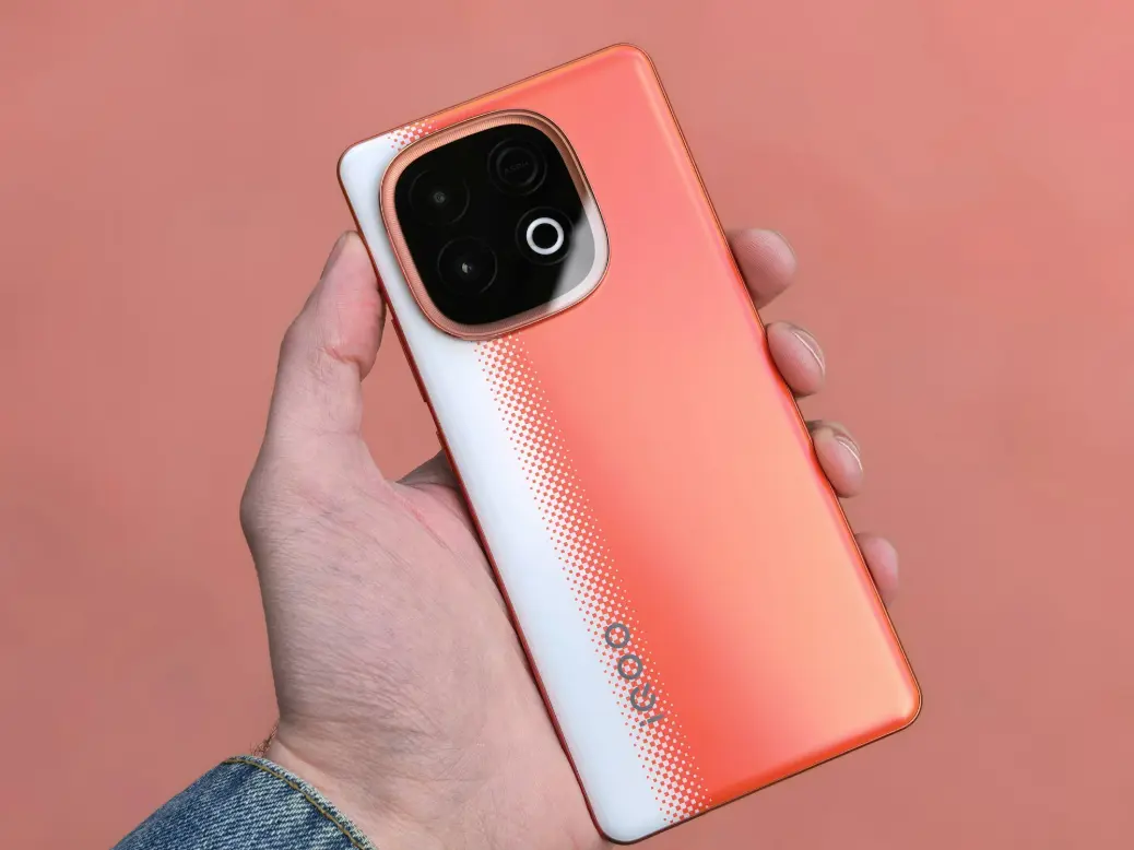 A hand holds an orange and white smartphone.