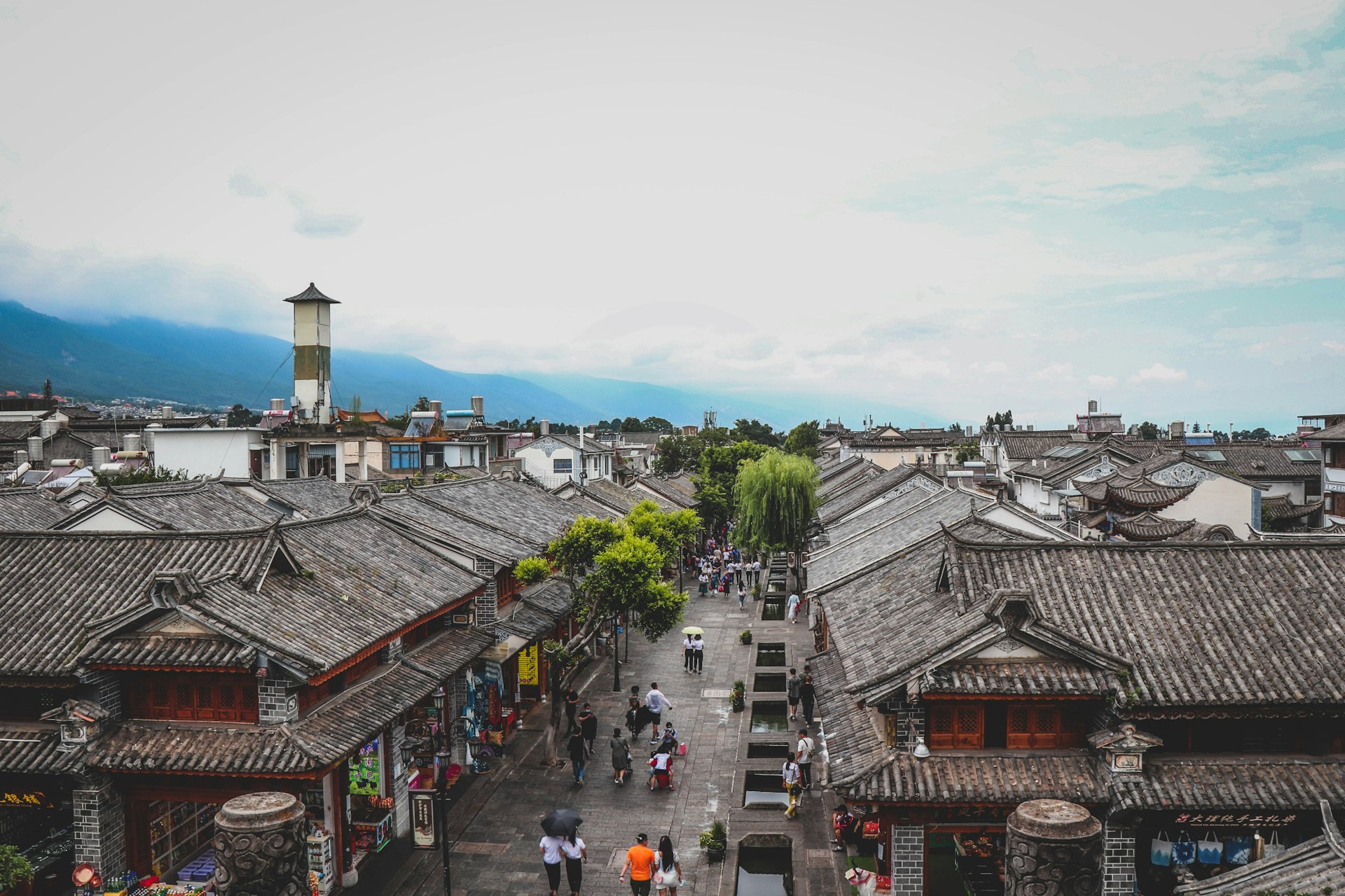 a group of people walking on a street between buildings